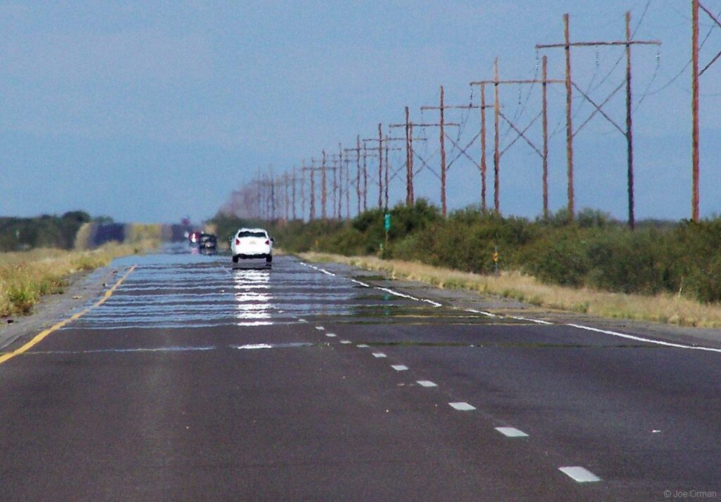 Photo of a mirage of water on a road.