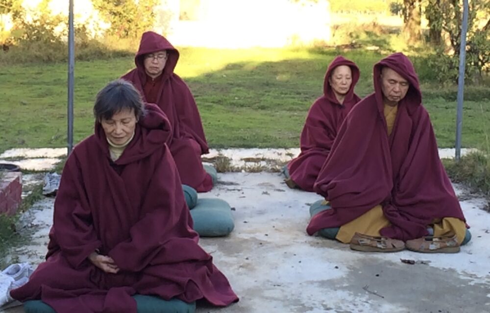 Photo of Pilgrims meditating with the Holy Vajra Poles.